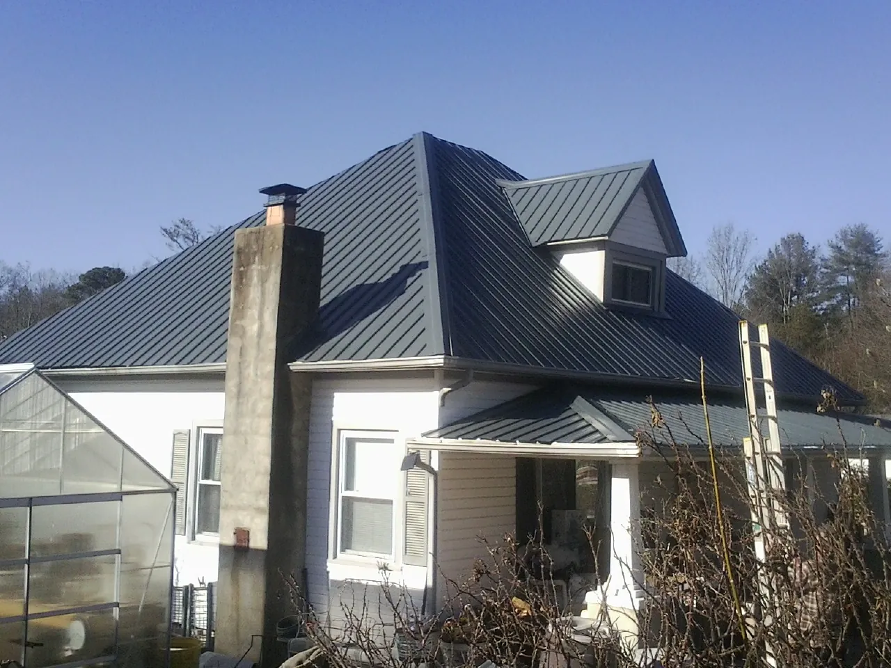 Dark blue standing seam metal roof on a white farmhouse with dormer — Slate & Tile Roof Repair by Roofing Brothers in Scott Depot