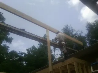Carpenter setting a ridge beam over a new addition frame — Ice Dam Removal by Roofing Brothers in Scott Depot