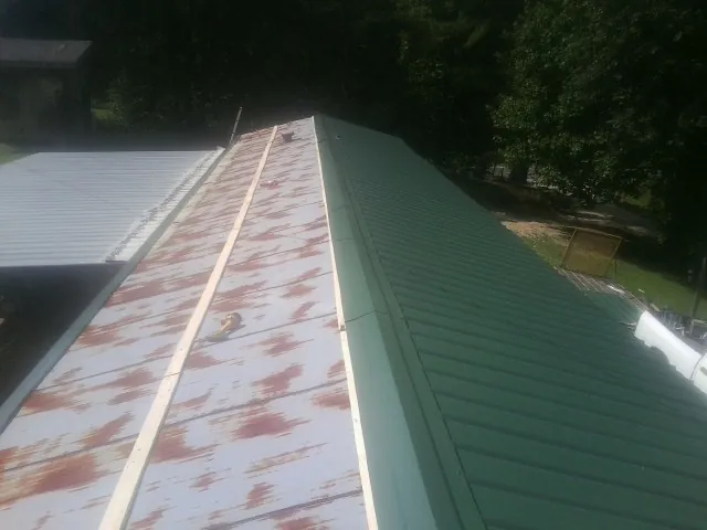 Old rusted panels beside newly installed green metal roofing — Wind Damage Roof Repair by Roofing Brothers in Scott Depot