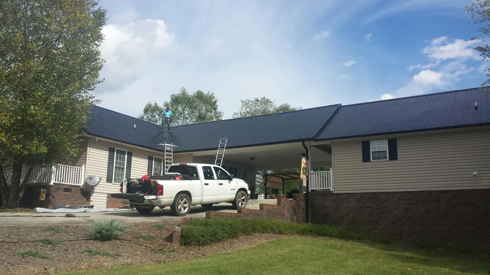 Black metal roof over a home and attached breezeway with ladders set in Scott Depot