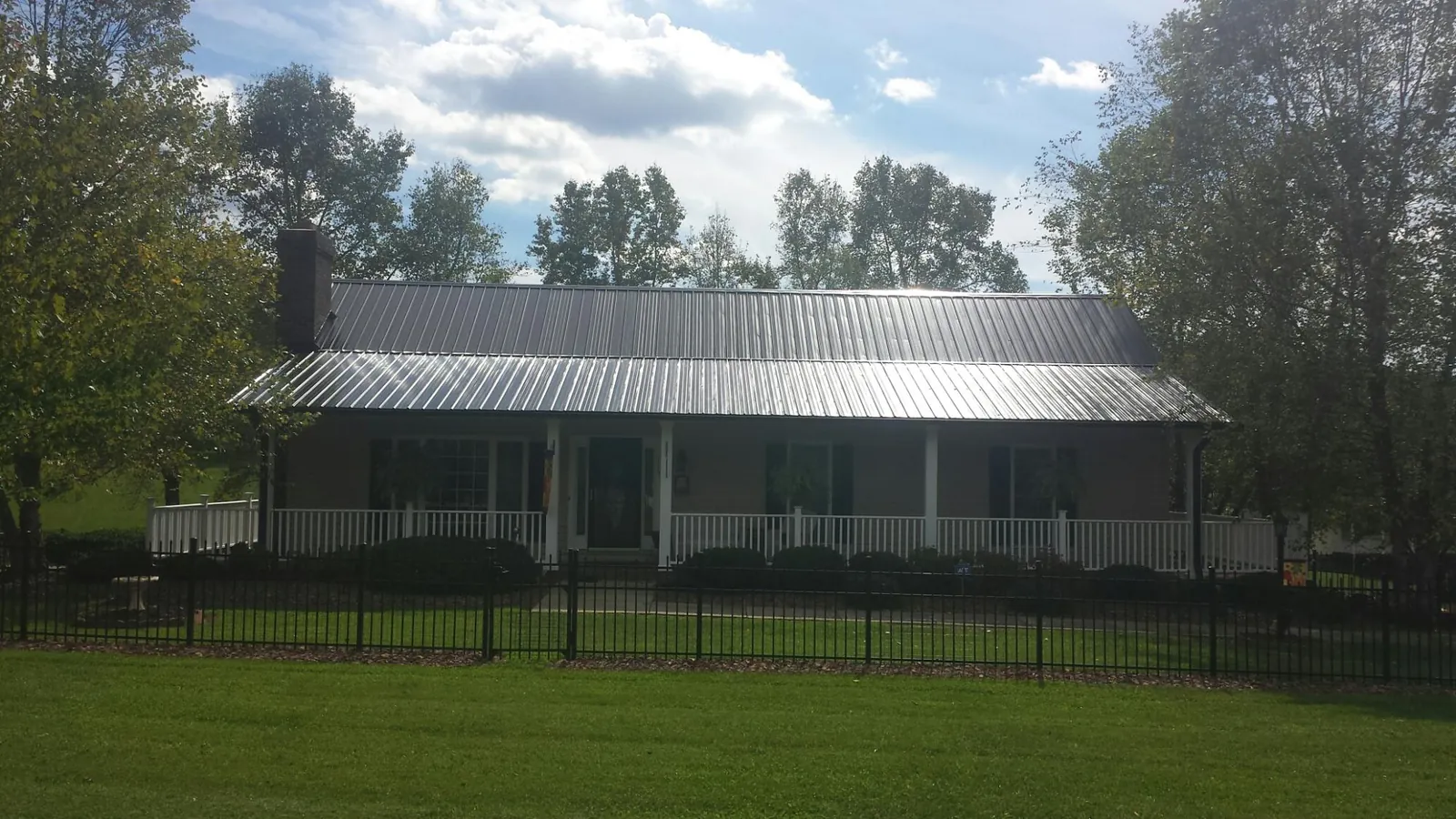 Gray metal roof on a brick ranch with a full width front porch — Gutter Guard Installation work by our crew in Scott Depot