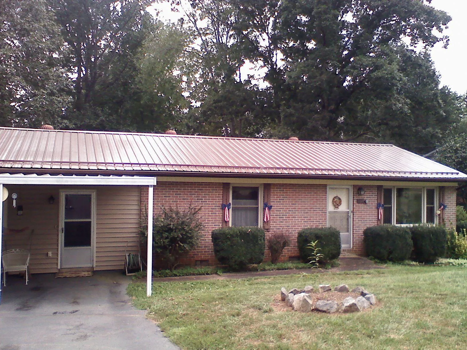 Bronze metal roof and carport on a brick ranch home — Roof Repair work by our crew in Scott Depot