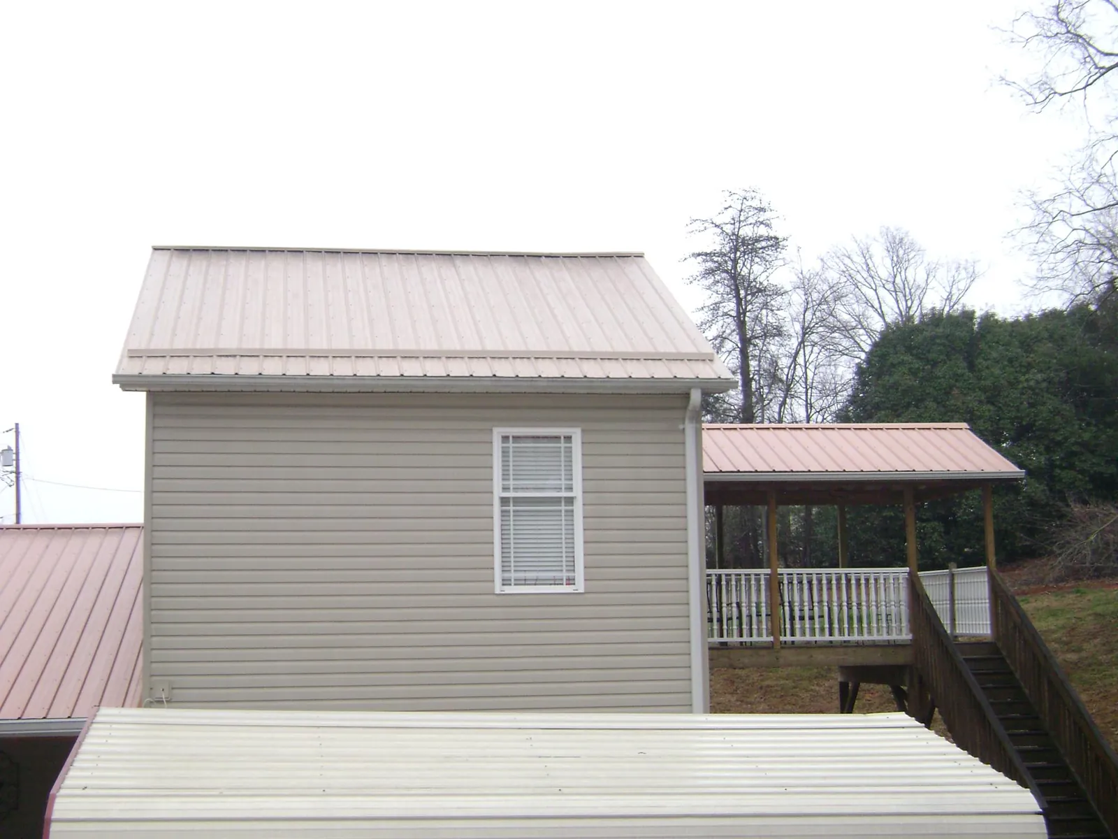 Tan metal roofs on a two story addition and attached porch, from a Roof Replacement job in Scott Depot