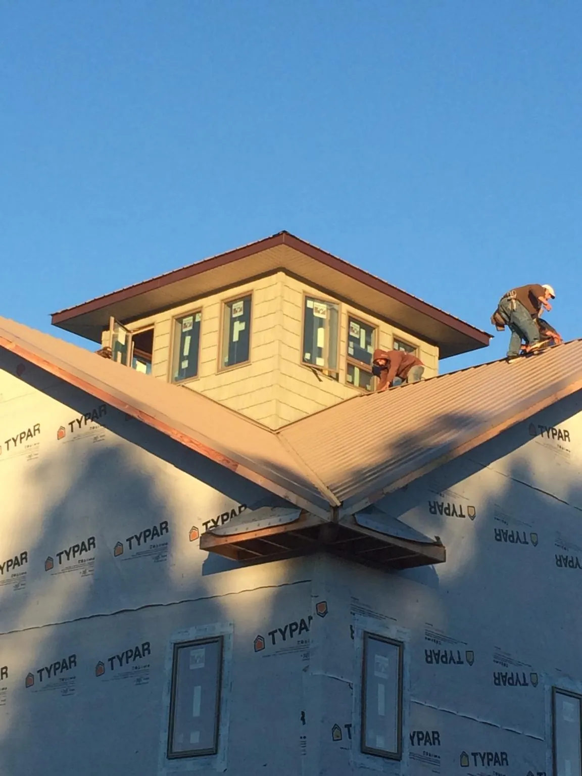 Roofers working around a rooftop cupola on a new metal roof at sunset — Roof Waterproofing in Scott Depot by Roofing Brothers